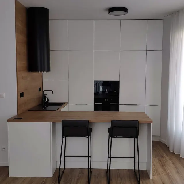 Biela kuchyňa s dubovým barovým pultom