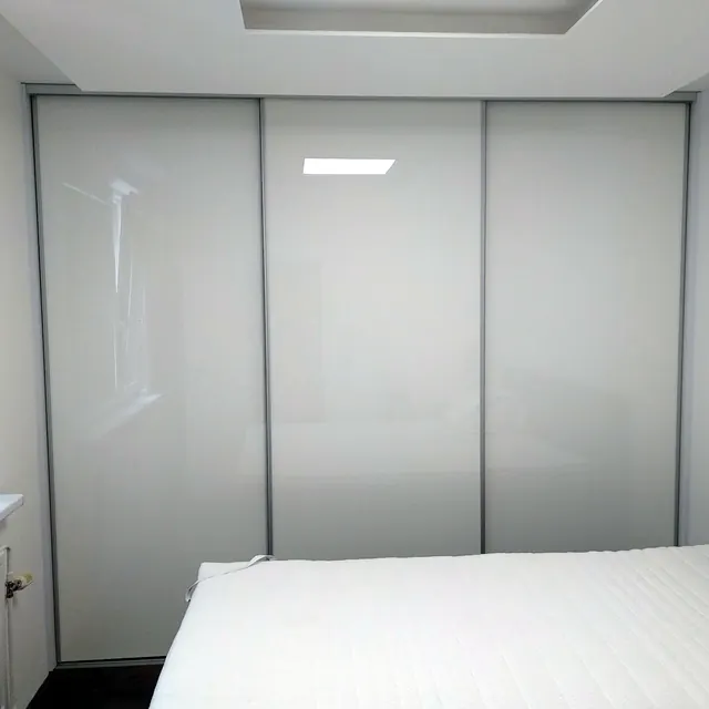 Biela lesklá skriňa s posuvnými dverami v spálni